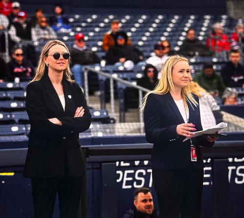 two people stand on the field at a baseball game