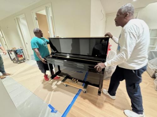 two piano movers moving a piano.