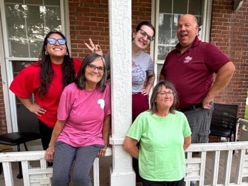 five employees posing outside their office.