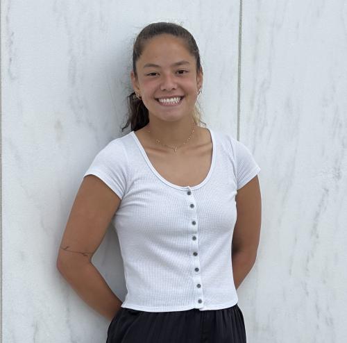 A female Oberlin student in a white shirt, standing in front of a white wall.