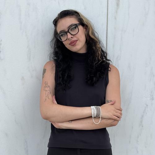 A female student in a black shirt standing in front of a white wall.