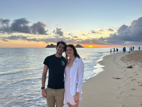 Aahil and Ava smiling in front of a beach