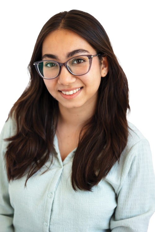 a person with long dark hair wearing glasses and a light-aqua t-shirt
