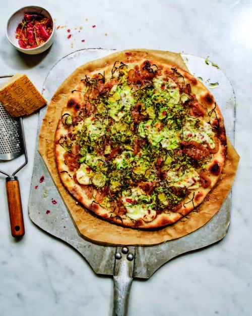 a pizza with veggies and greens on a silver pizza tray