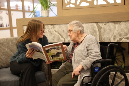 Oberlin student participating in a Winter Term Micro-Internship at Kendal at Oberlin by reading with a resident.