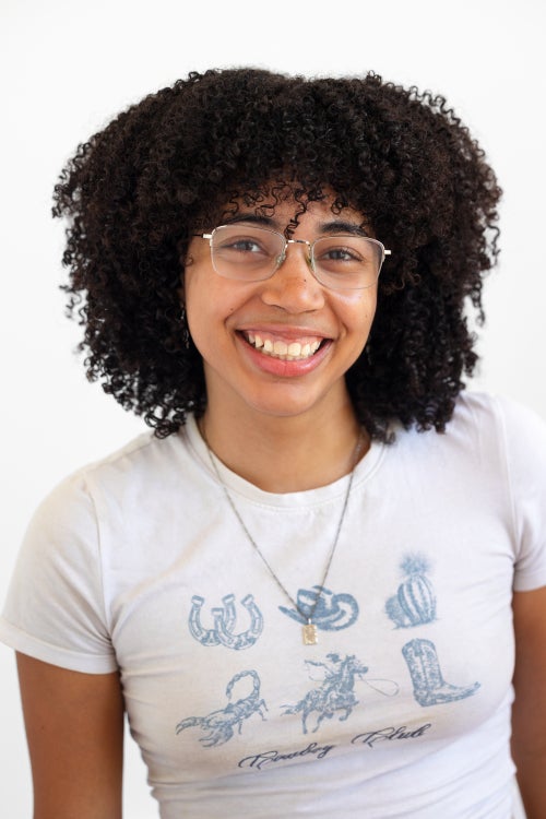 Olivia Hood is smiling and wearing a white graphic tee.