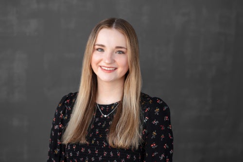 Sammi Quinn smiling in a black blouse with a floral pattern.