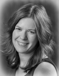 black and white photo of woman with long hair, smiling at camera