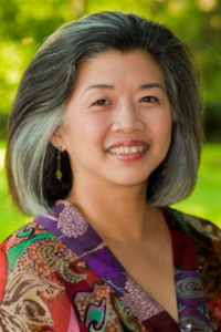 Woman with black and gray hair, wearing a multicolored dress
