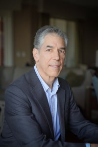 photo of man with greying hair, wearing shirt and suit coat