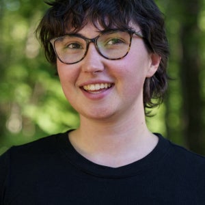 Ozzie wearing a black shirt and glasses in front of a green background. 