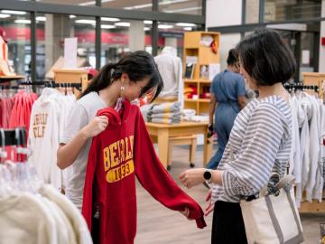 student and parent perusing clothing in a store.