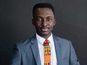 a person wearing a gray suit coat, white shirt and colorful tie