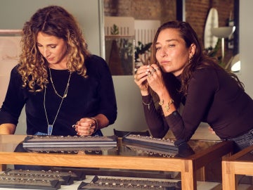 Two women working at a jewelry workbench, examining tools and materials together.