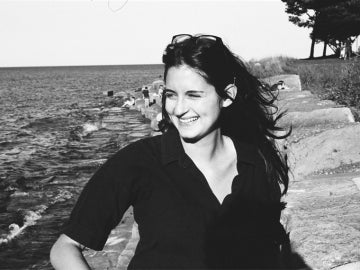 a person wearing a black shirt looks to the left in front of water