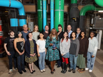 students and staff pose for a photo with a glass statue inside Oberlin's heating and cooling plant.
