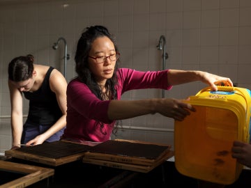 a person in a magenta shirt works making paper