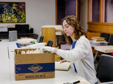 Student sorts files at desk.