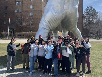 Bonner Scholars pose as a group underneath a giant hand sculpture.