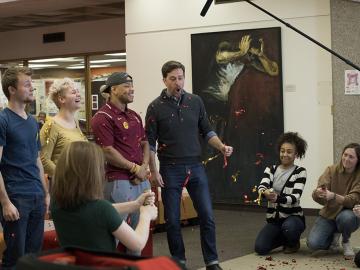 A video crew tosses confetti while alumnus Ed Helms is on camera with students.