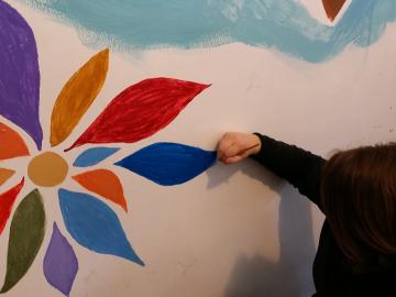 Student painting a flower on a wall 