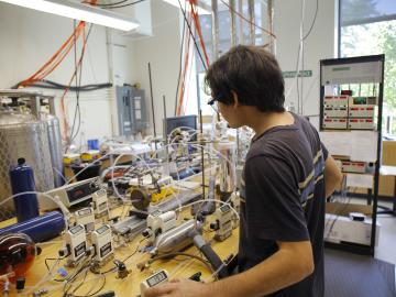 William Burke makes adjustments to instruments in Matthew Elrod’s lab.