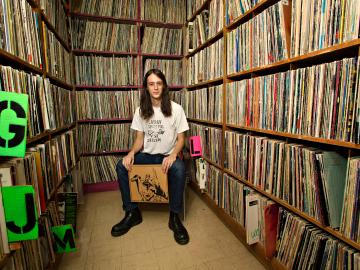 Adrian Rew ’13 surrounded by shelves full of LP records