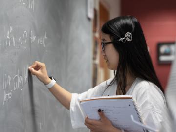 Alina Zhu writing at a chalkboard.