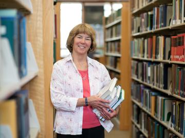 Picture of woman holding a stack of books in library
