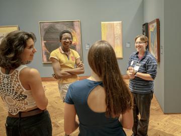 Students cheerfully discussing art in a campus gallery.