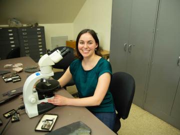 Amelia Lewis smiling, seated at a desk in the geology lab