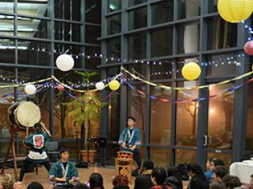 People watch Taiko drummers under festive decorations.