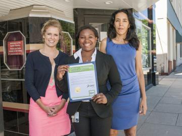 Serena Hendricks outside of the Apollo Theatre holds a certificate of commendation presented by a representative from the office of Secretary of State John Husted