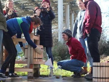 A group of students using a hand-cranked cider press.
