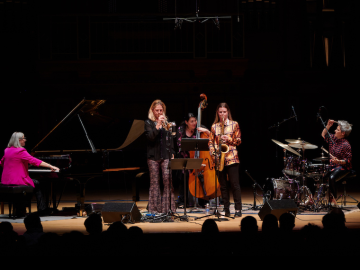 five women performing piano, bass, drums, trumpet, and sax on Finney stage