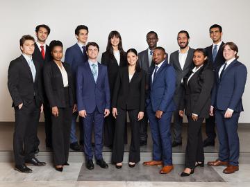 a group of 13 students wearing business attire standing in a group