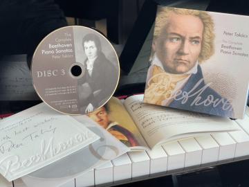 CD and package placed on a piano keyboard.