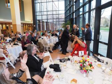 People gathered for a banquet in a large empty room, applauding