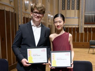 Young man with glasses and dark hair and young woman with dark hair holding certificates