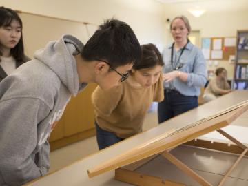two students bent over looking at a lithograph.
