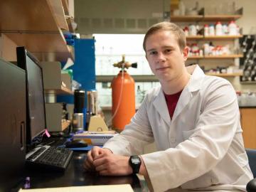 Photo of man sitting at a computer in science lab