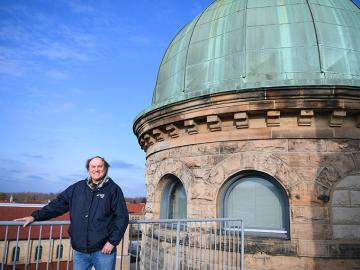 man standing next to a observatory dome