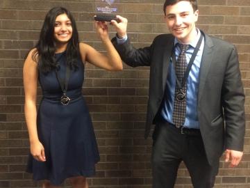 Yasmine and Aaron hold up an award.
