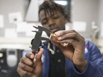 Close-up photo of Daniel Mukasa working with tools in the lab