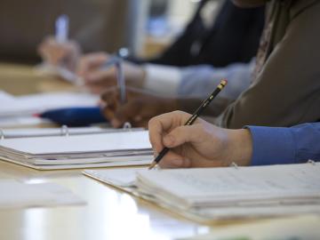 Close-up of students taking notes at desks