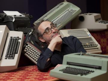 Gary Shteyngart makes a silly, introspective pose amidst typewriters 