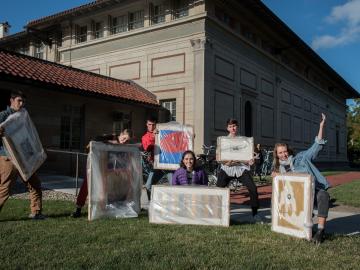 students on lawn holding art work
