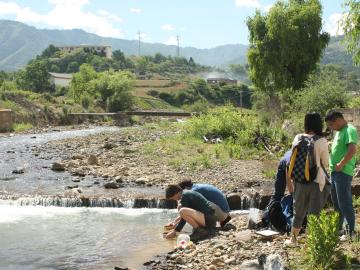 Students taking soil samples from the edge of a river