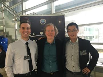 Two male students pose on either side of their male professor