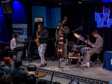 jazz ensemble—sax, piano, bass, and drums—on stage